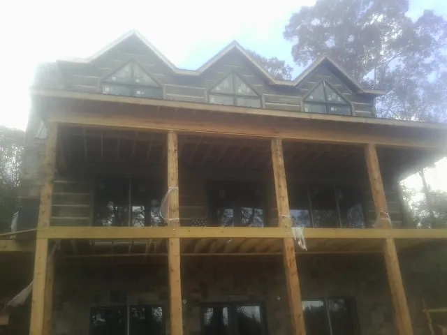 Dormers and porch framing on a large log home under construction — Roof Coating work by our crew in Bellwood