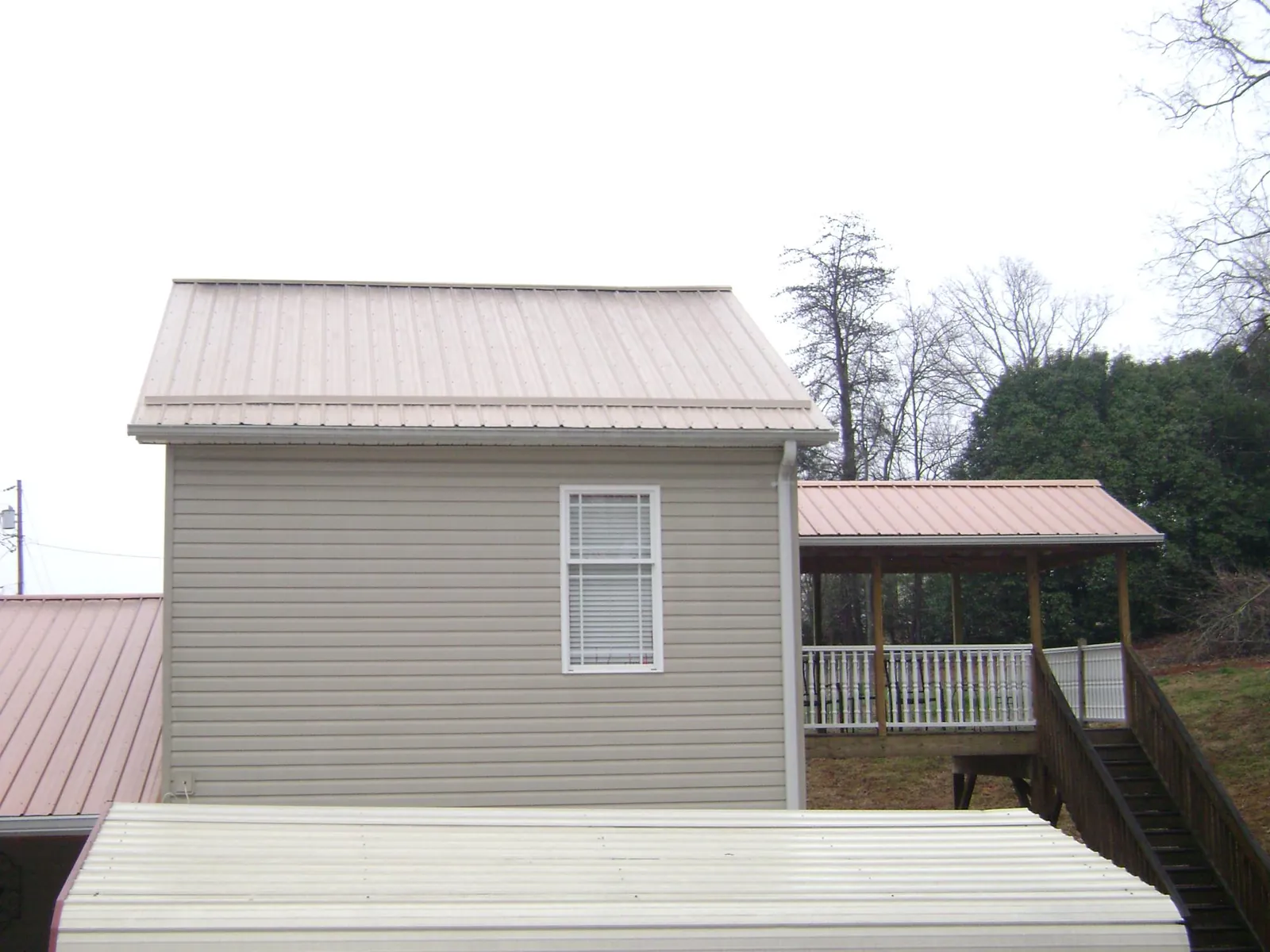 Tan metal roofs on a two story addition and attached porch, from a Roof Replacement job in Bellwood